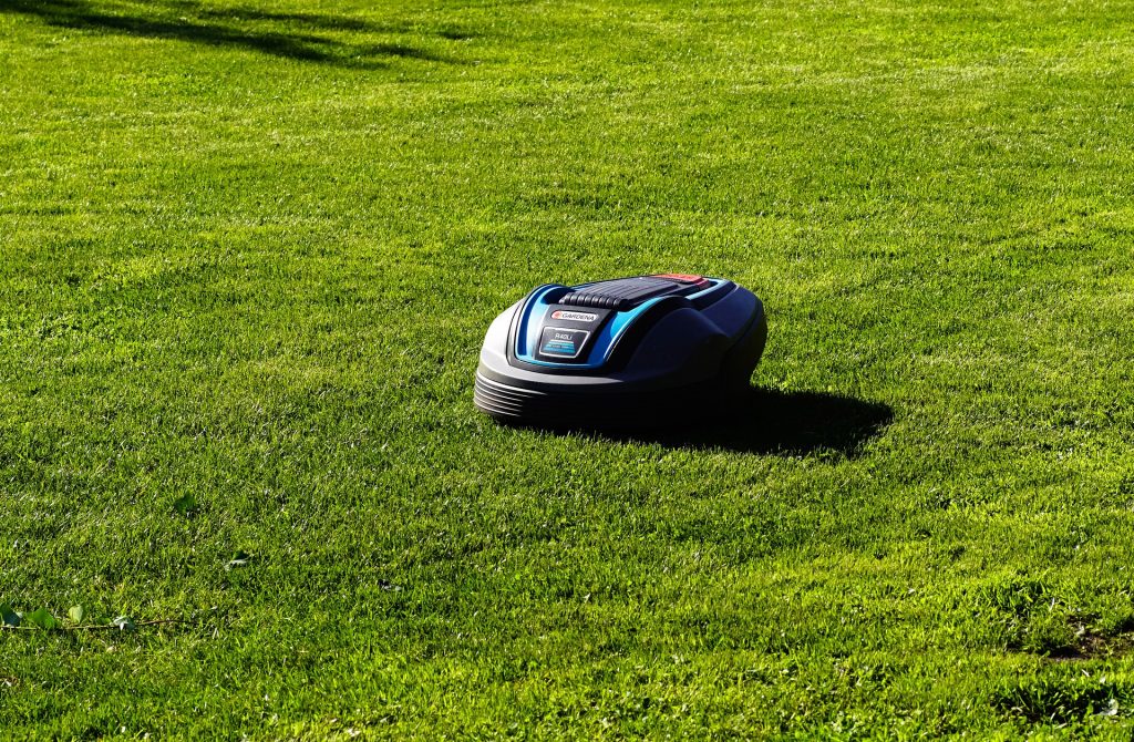 Robot tondeuse Gardena en train de tondre l'herbe sur un terrain plat